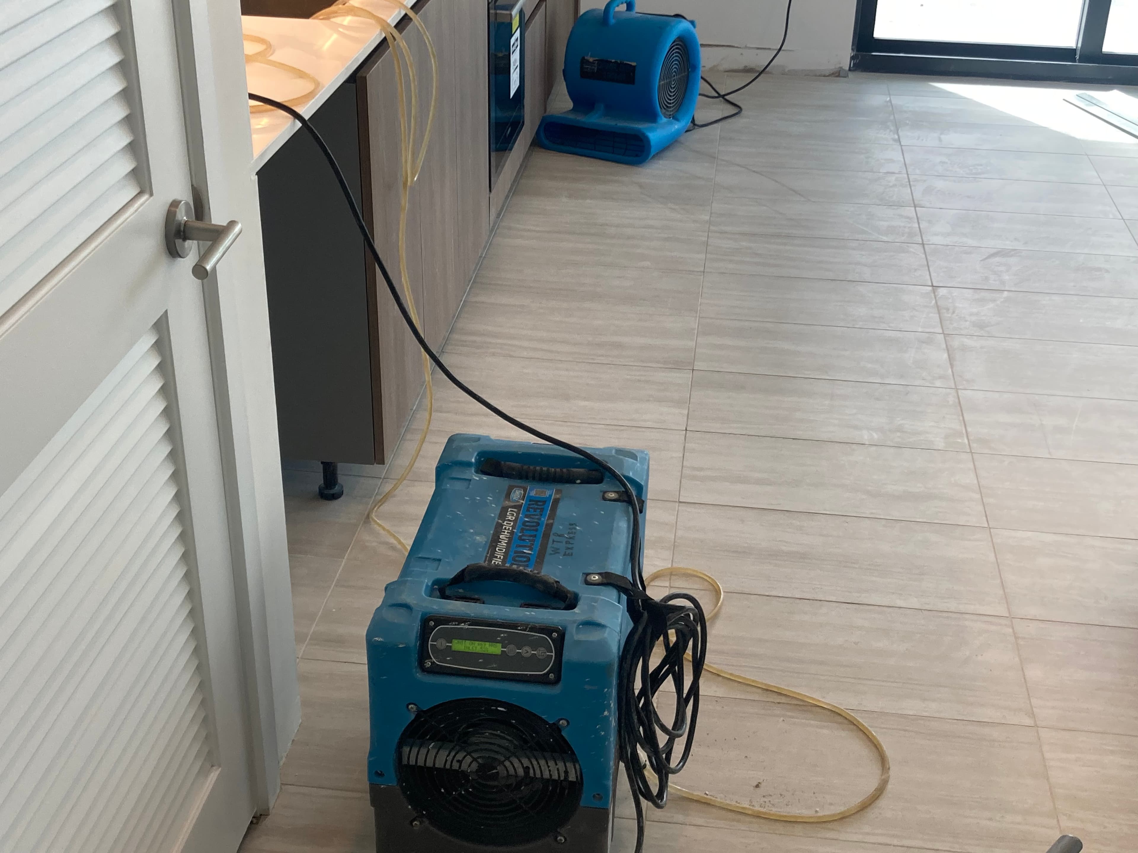 Commercial dehumidifier and air mover operating in kitchen after South Florida water loss