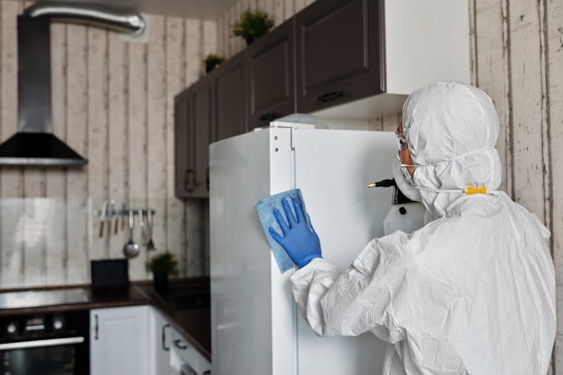 Hazmat-suited worker decontaminating a NYC kitchen during biohazard cleanup